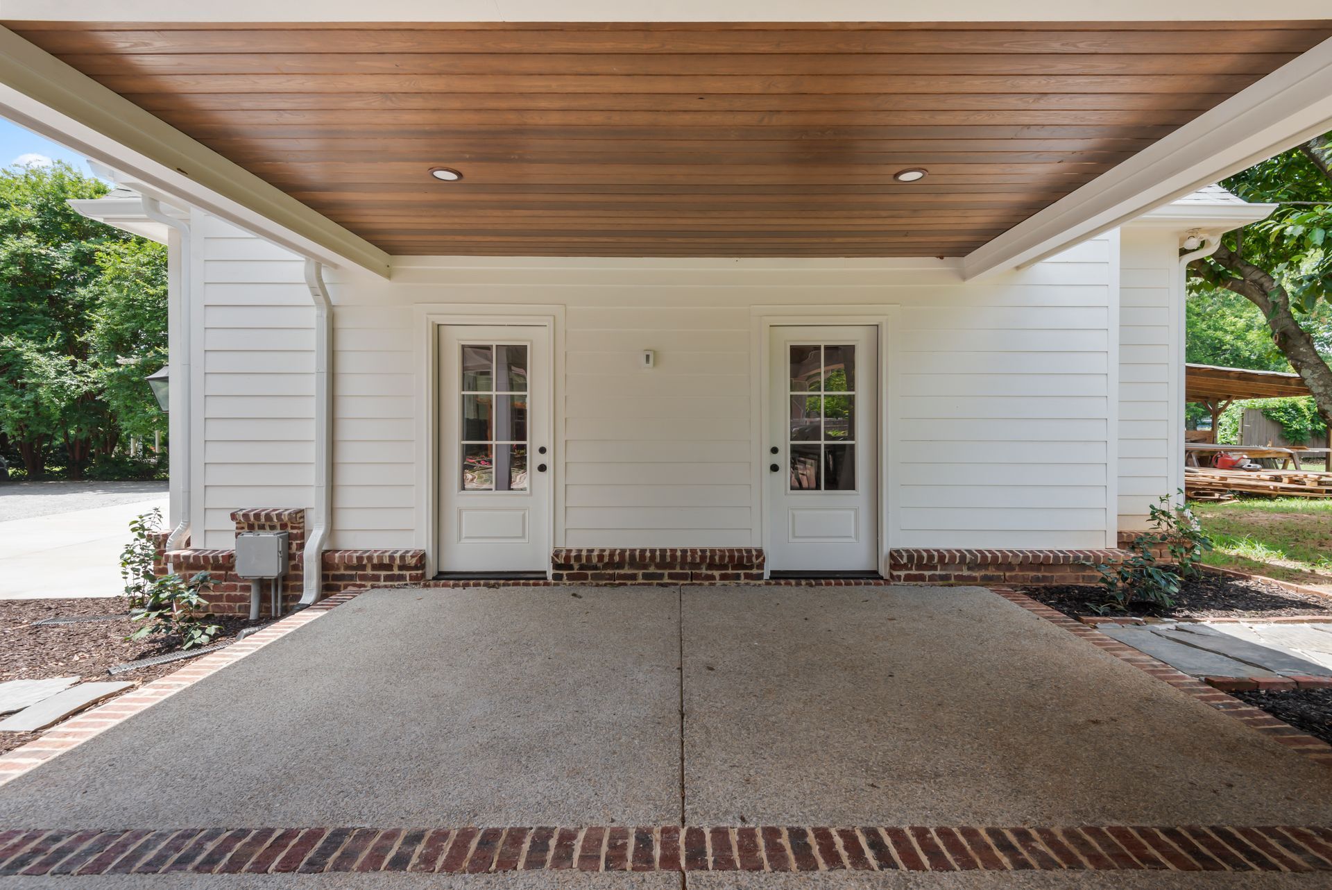 A white house with a wooden ceiling and a driveway leading to it.