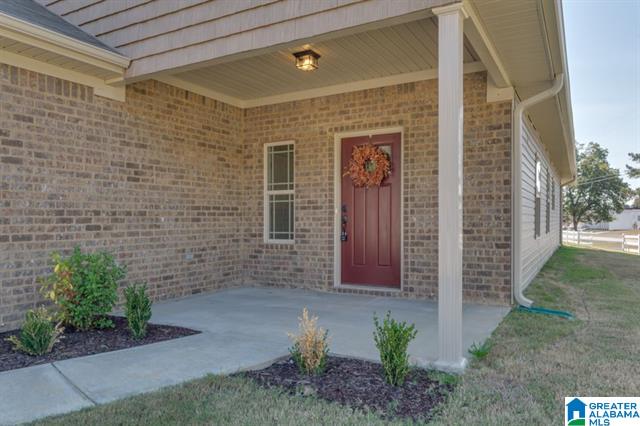 the front porch of a brick house with a red door and a wreath on it .