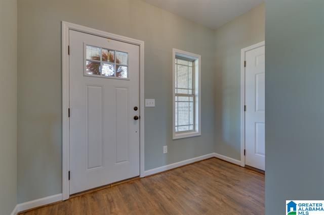 a hallway in a house with a white door and two windows .