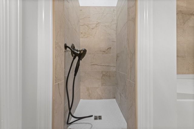 A bathroom with a shower and a hair dryer. By Mims custom home construction