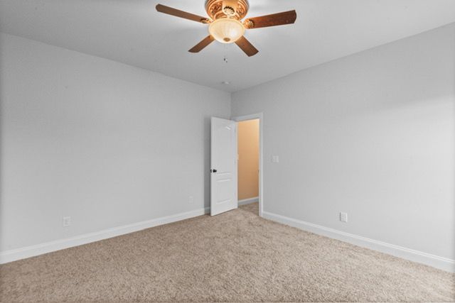 An empty bedroom with a ceiling fan and a door. By Mims custom home construction