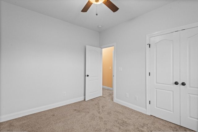 An empty bedroom with white walls and a ceiling fan. By Mims custom home construction