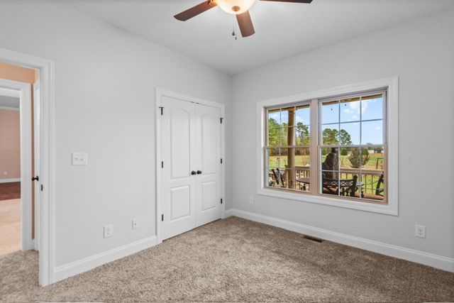 A bedroom with a ceiling fan and a large window. By Mims custom home construction