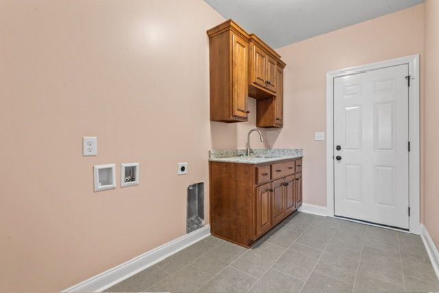A laundry room with wooden cabinets and a sink By Mims custom home construction