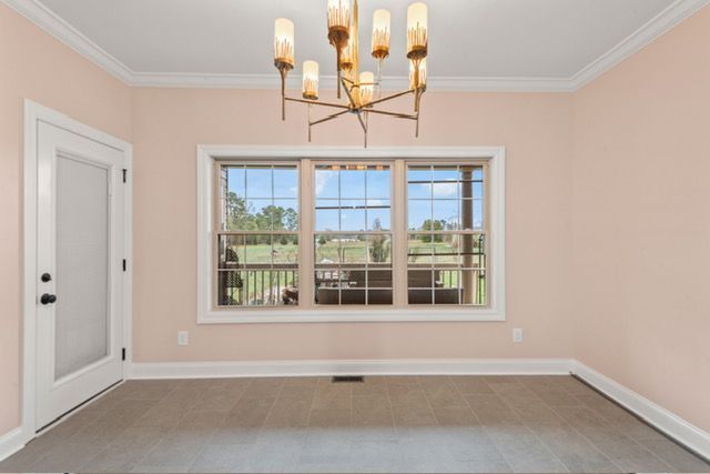 An empty room with a large window and a chandelier By Mims custom home construction