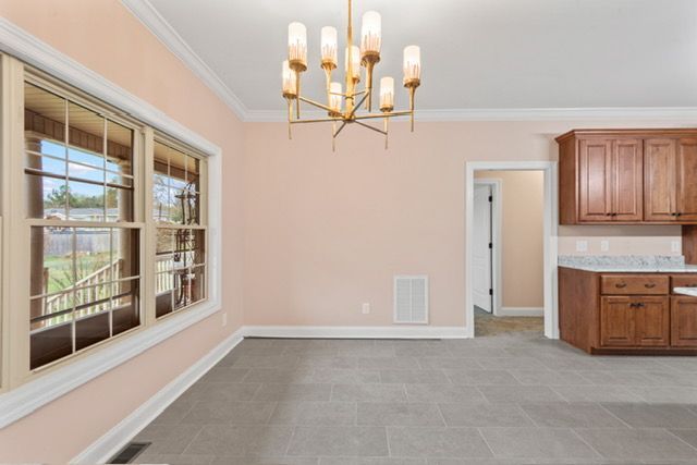 An empty room with a chandelier hanging from the ceiling By Mims custom home construction