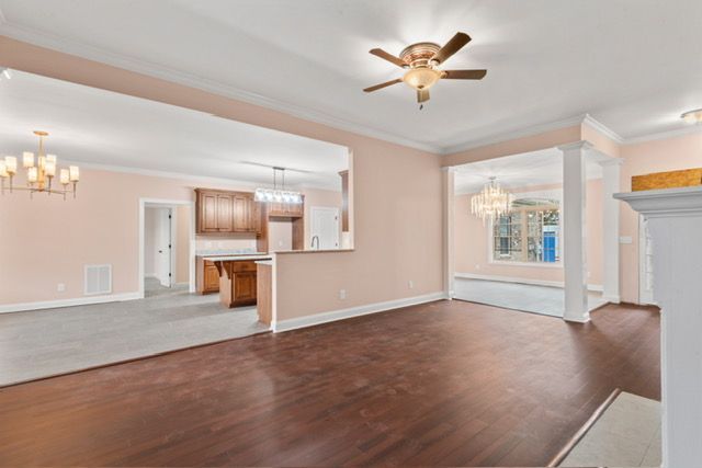 An empty living room with hardwood floors and a ceiling fan. By Mims custom home construction
