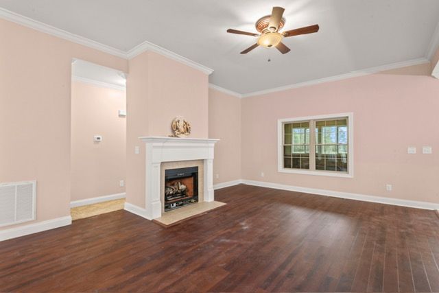 An empty living room with a fireplace and ceiling fan. By Mims custom home construction