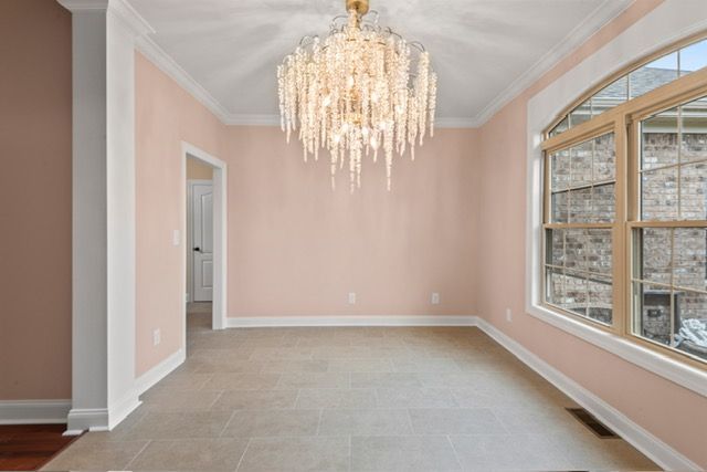 An empty room with pink walls and a chandelier hanging from the ceiling. By Mims custom home construction