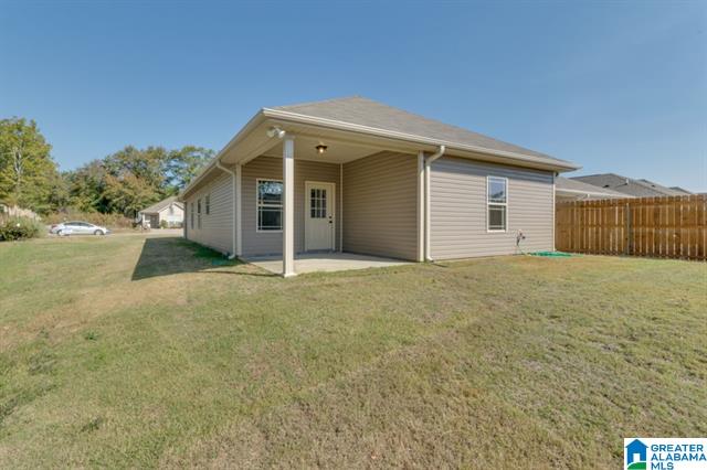 the back of a house with a porch and a fence .