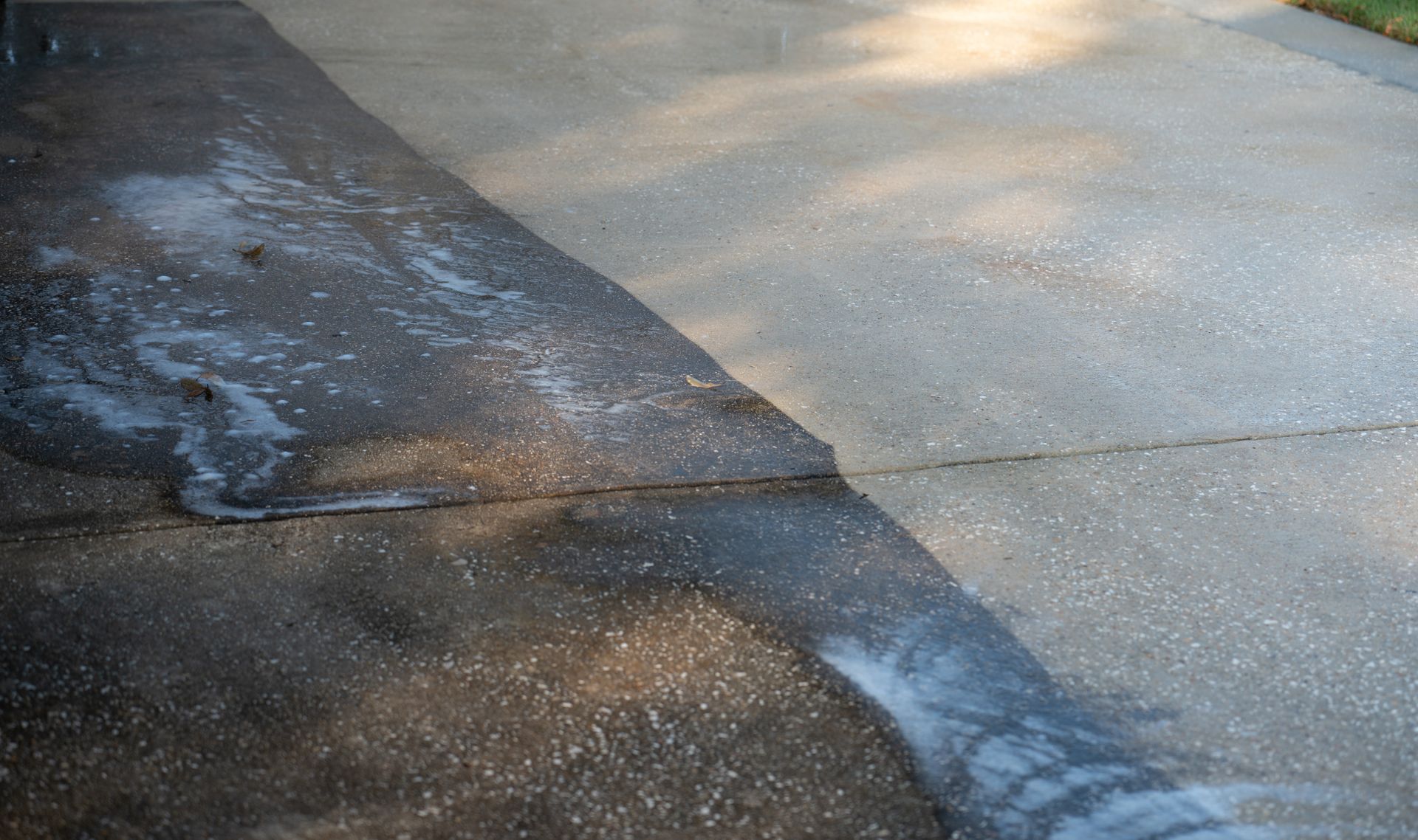 A concrete driveway is being cleaned with a pressure washer.