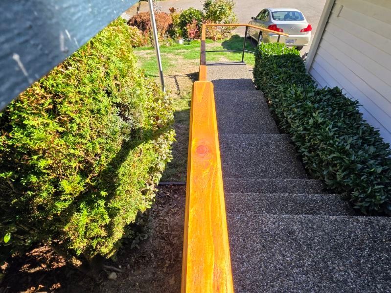 A wooden railing on a set of stairs leading up to a house.
