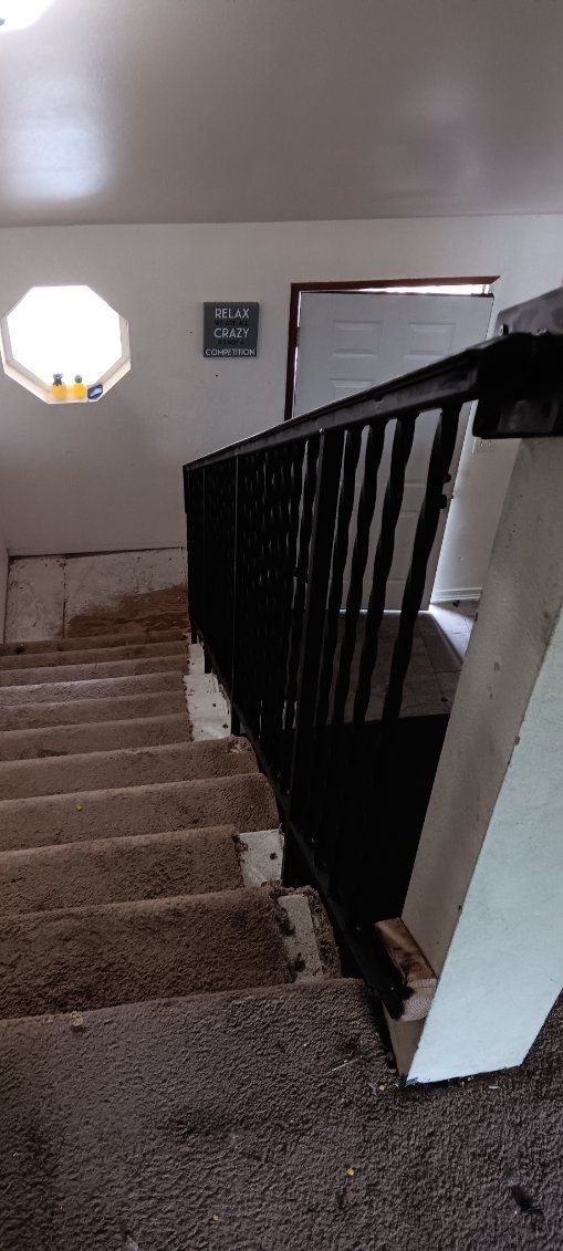 A staircase with a black railing and a carpeted floor in a house.