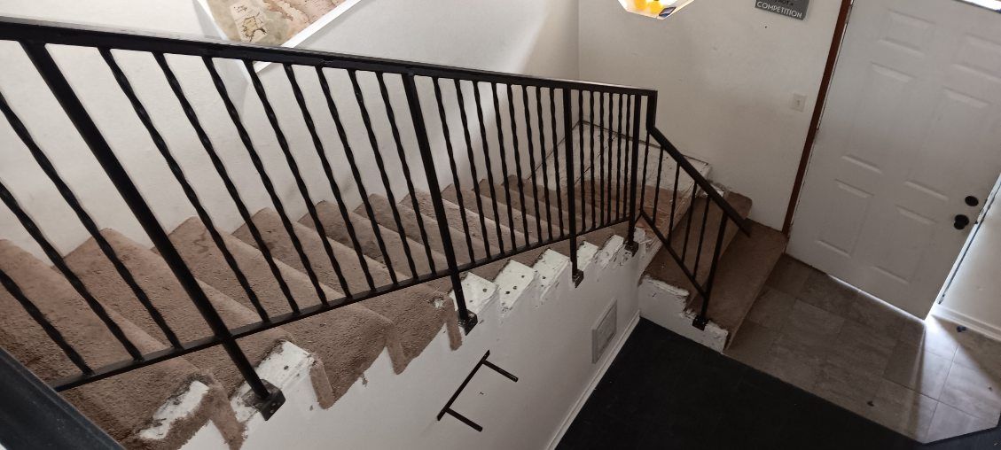 A staircase with a metal railing and carpeted steps in a house.