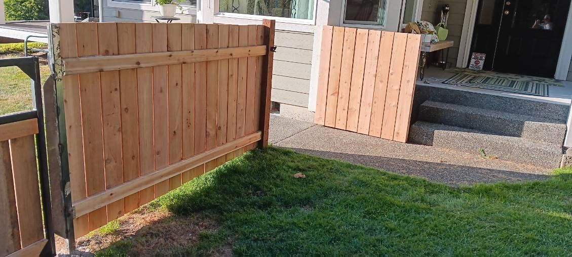 A wooden fence is sitting in the grass in front of a house.