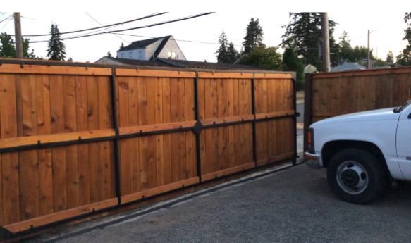 A white truck is parked in front of a wooden fence.