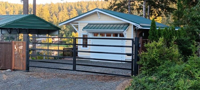 A white house with a green roof and a black gate in front of it.