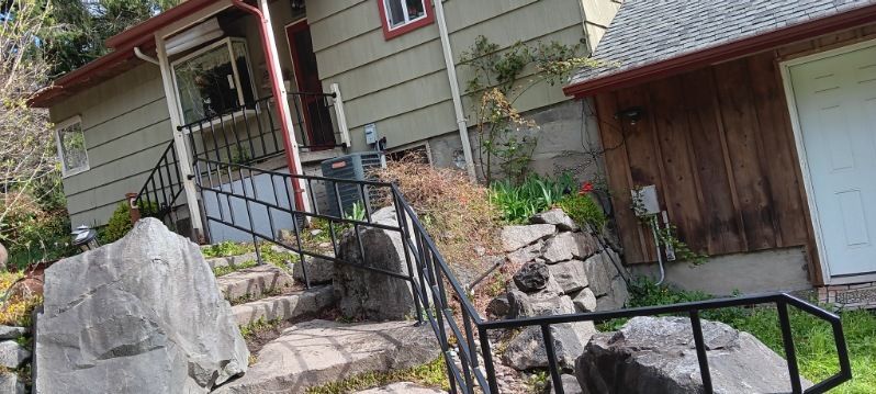 A house with stairs leading up to the front door and a metal railing.