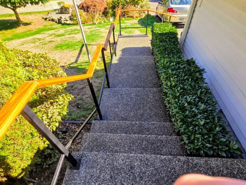 A set of stairs leading up to a house with a yellow railing.