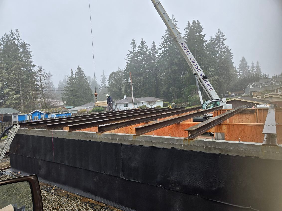 A crane is lifting a beam on top of a building.