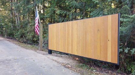 A wooden fence is sitting on the side of a road next to an american flag.