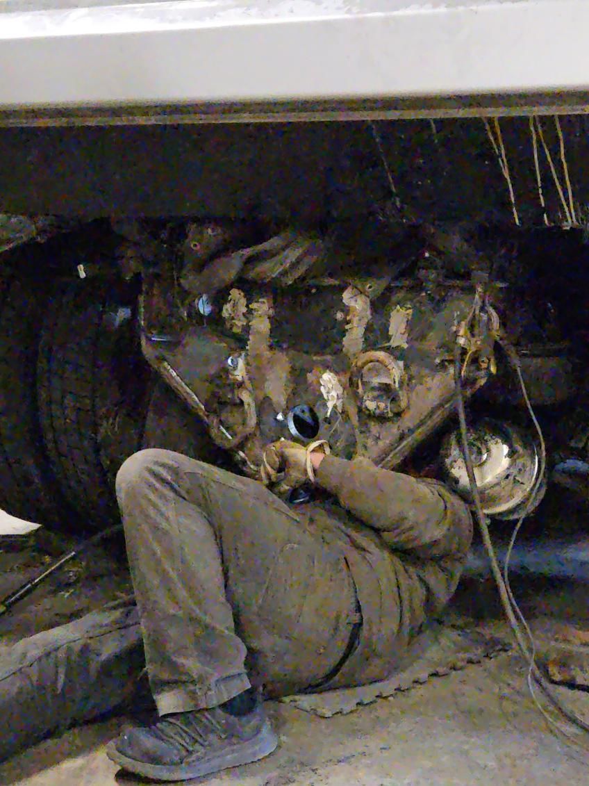 A man is working under a car in a garage.