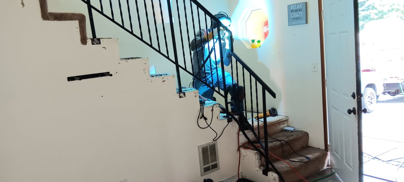 A man is welding a metal railing on a set of stairs.