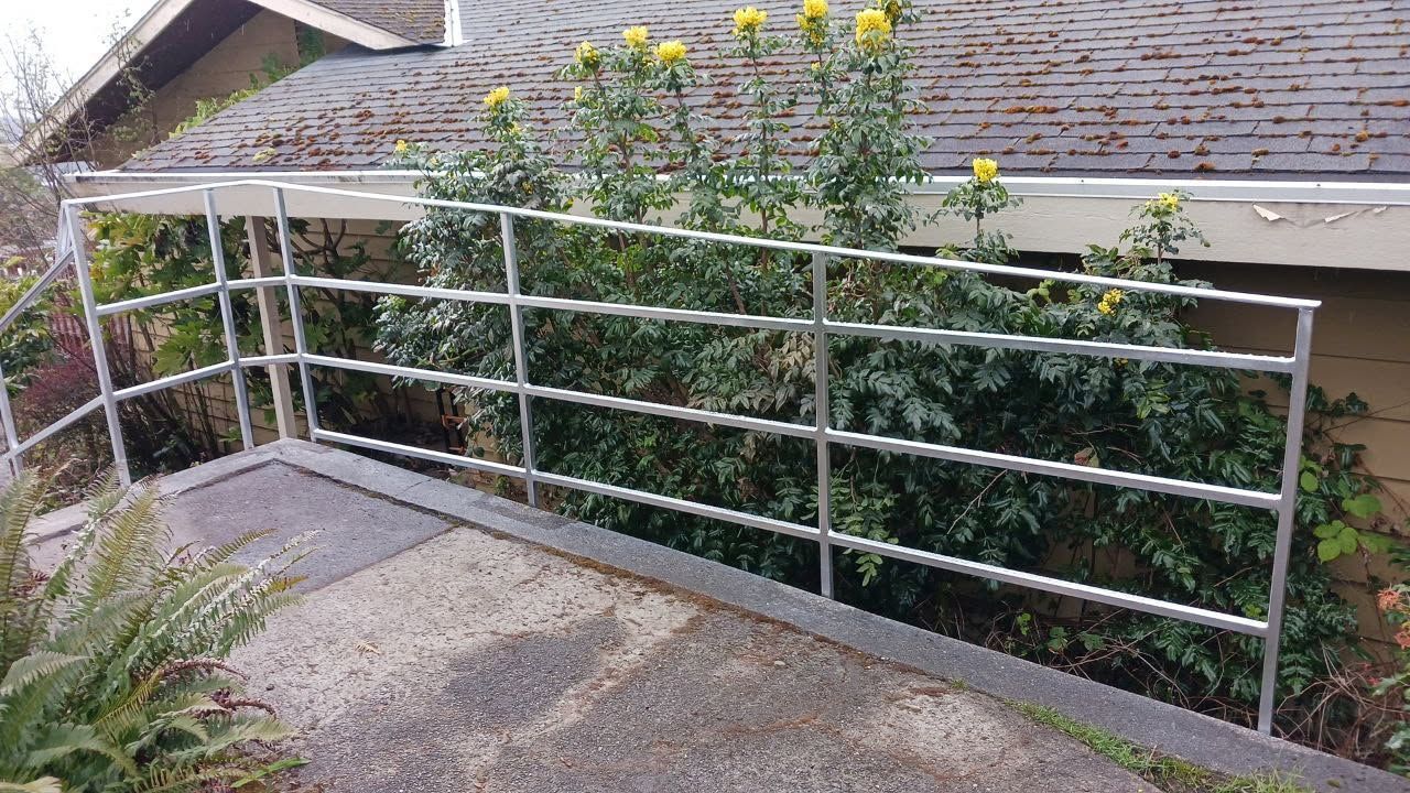 A metal railing surrounds a ramp leading to a house.