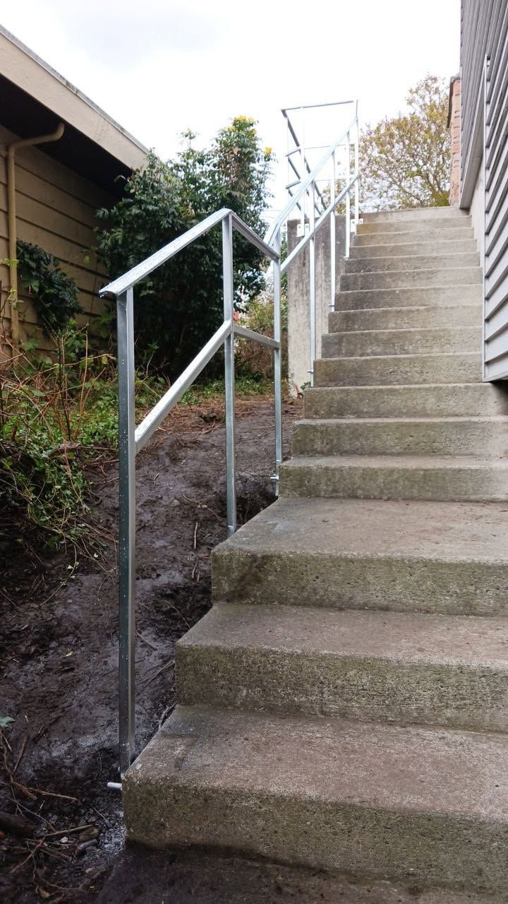 A set of stairs with a metal railing leading up to a house.