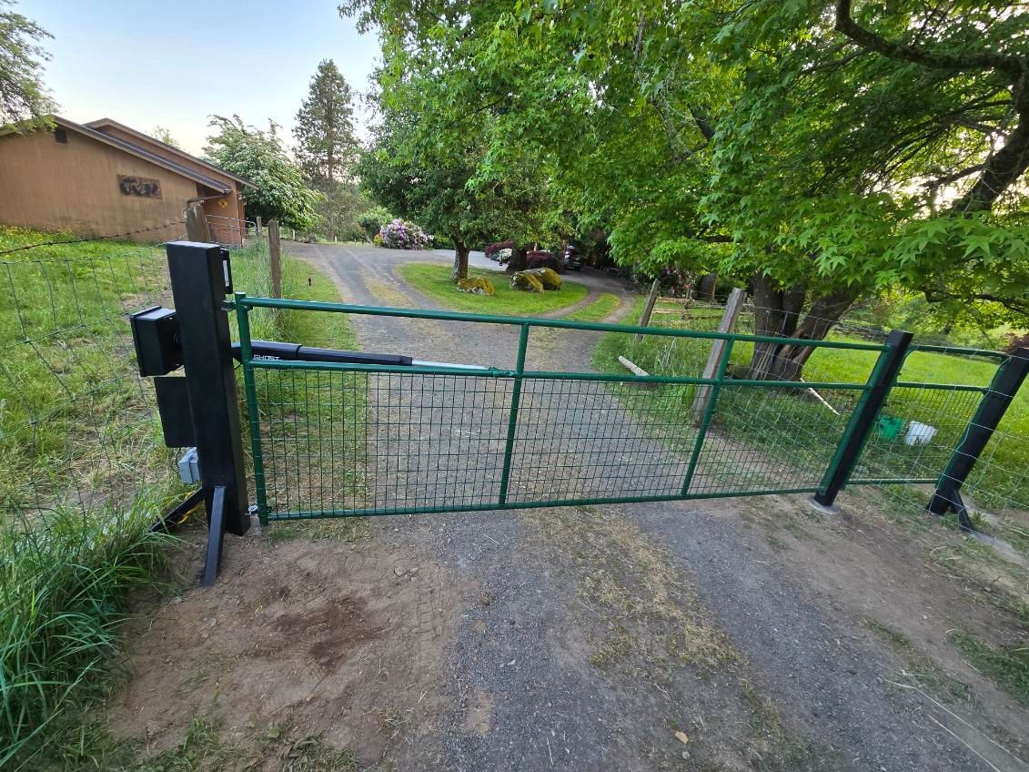 A green gate is open to a dirt road.