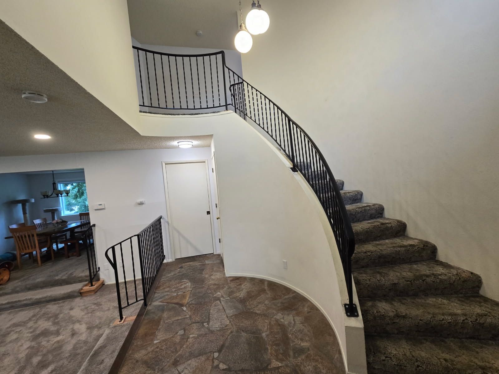 A curved staircase with a wrought iron railing in a house.