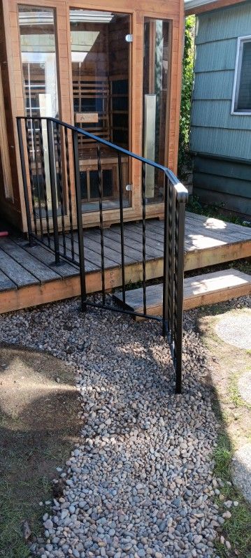 A wooden deck with a metal railing and stairs leading to it.