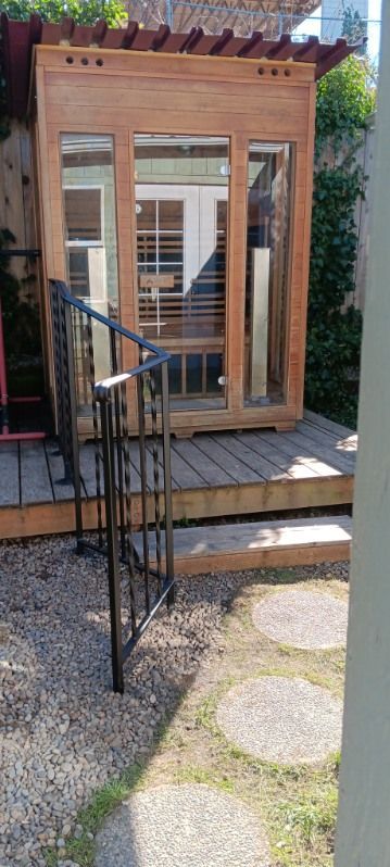 A wooden house with stairs leading up to it in a backyard.