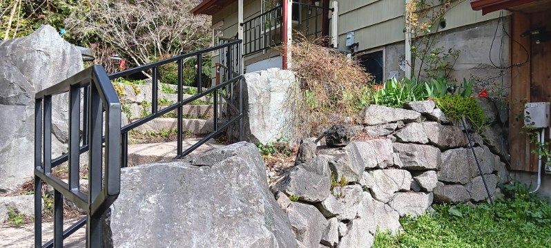 A house with a stone wall and stairs leading up to it.