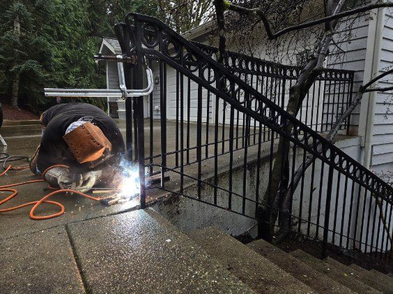A man is welding a railing on a set of stairs.