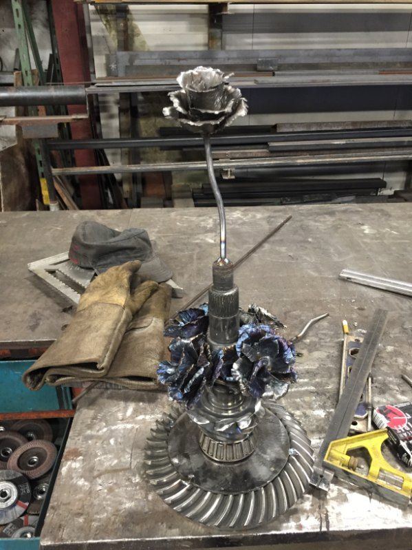 A metal flower is sitting on top of a gear on a table.