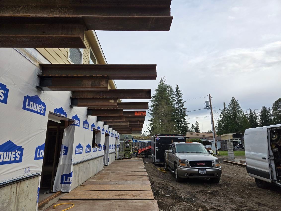 A white van is parked in front of a building under construction.