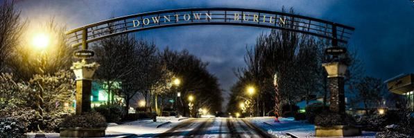 A bridge over a snowy street with trees in the background and a sign that says `` welcome ''.