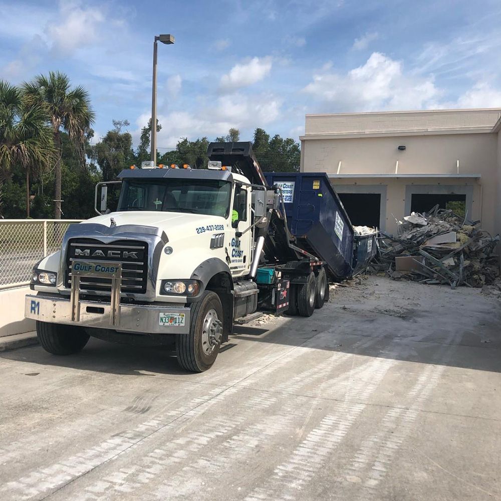 A service truck unloading a roll off dumpster rental in Naples, FL
