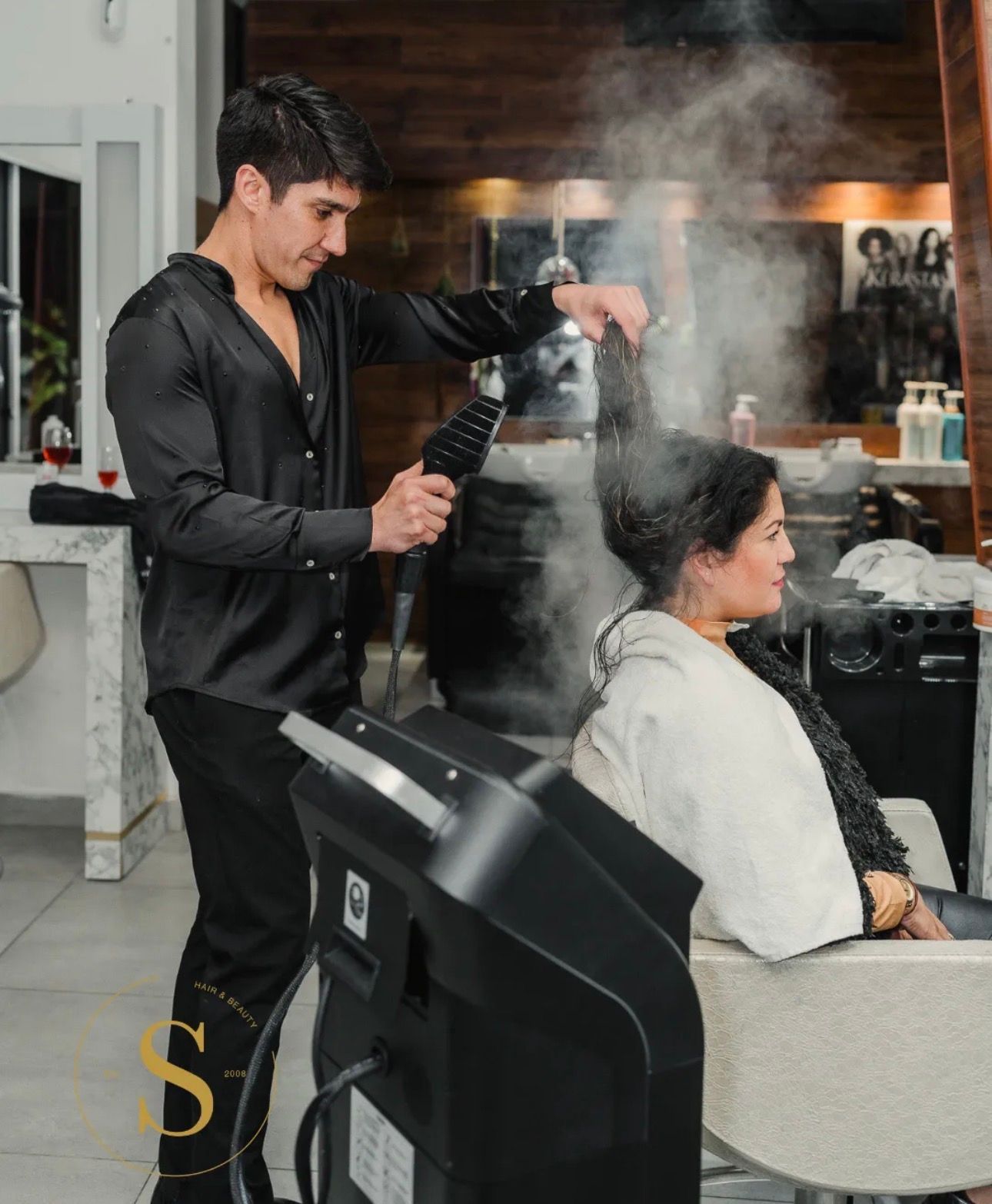Dos hombres están secando el cabello de una mujer en un salón.