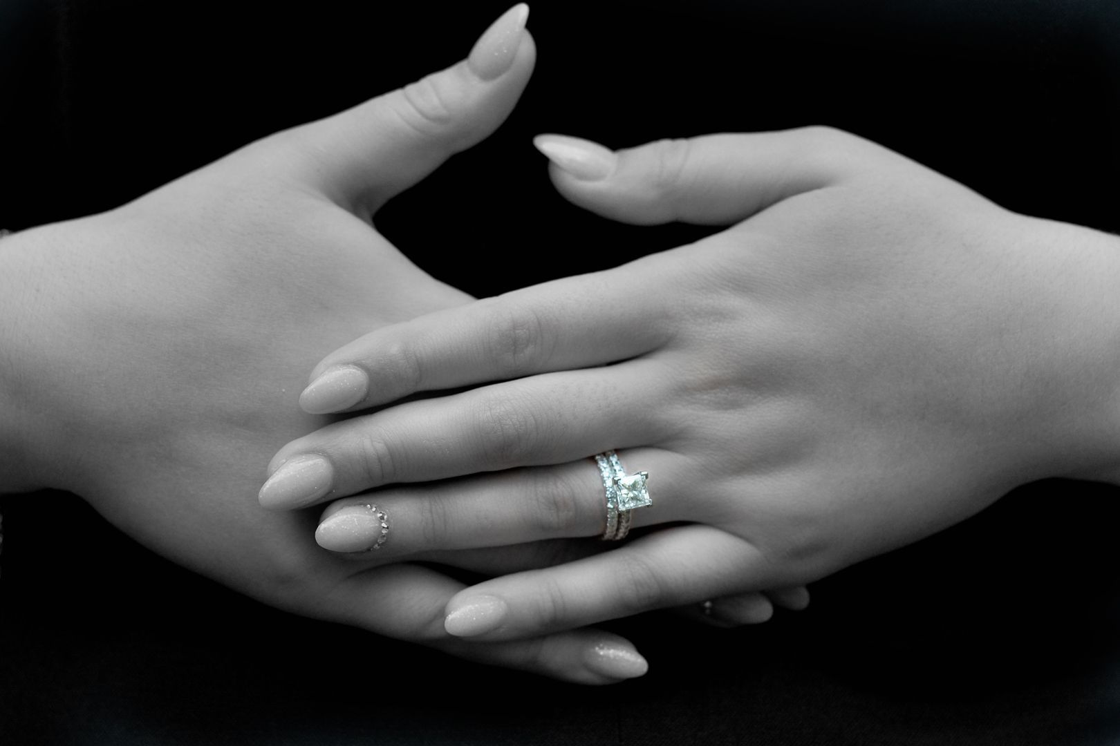 A bride and groom are holding hands with their wedding rings on their fingers.