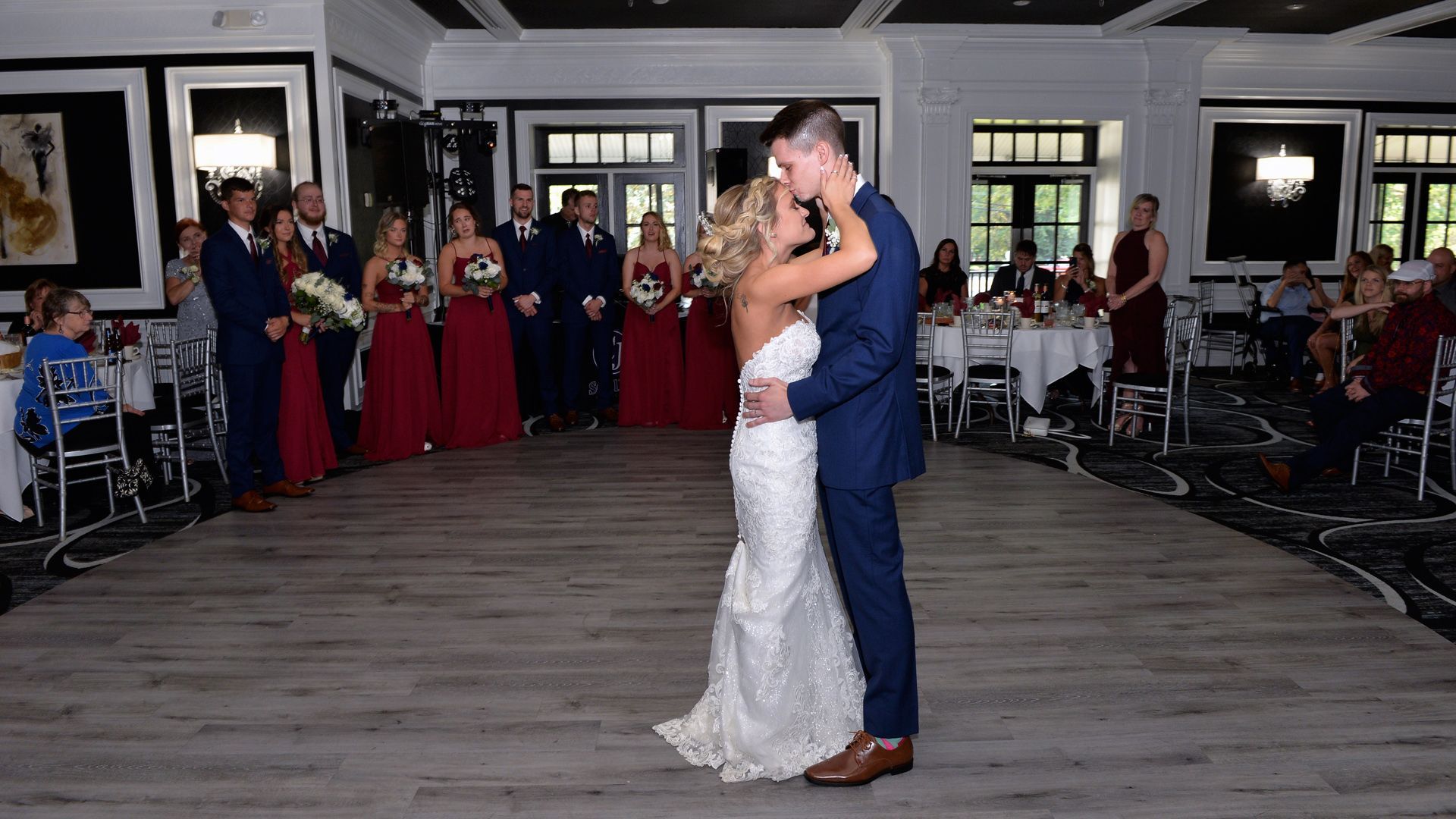 A bride and groom are dancing in front of a crowd at their wedding reception.