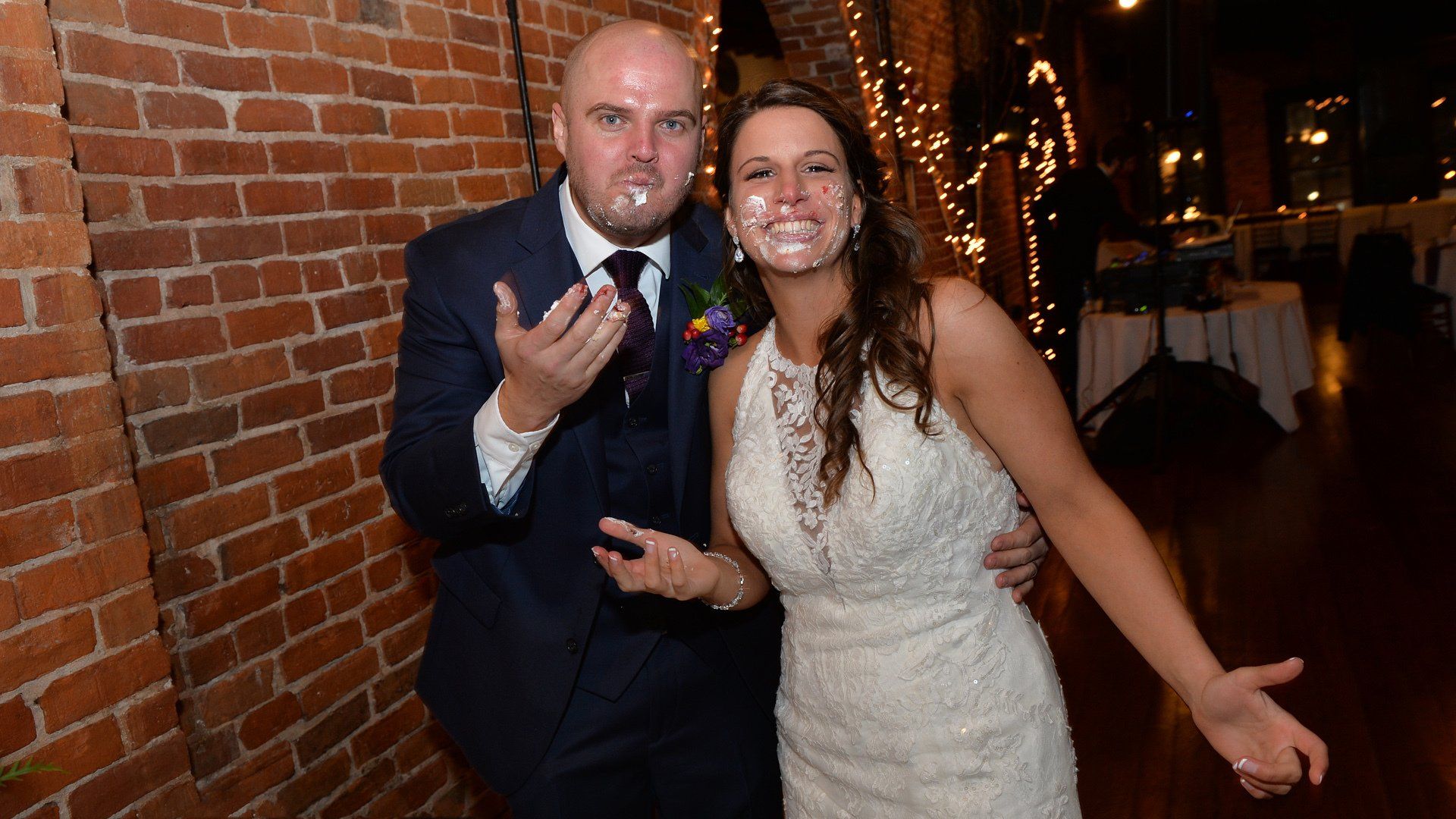 A bride and groom are posing for a picture with cake on their faces.