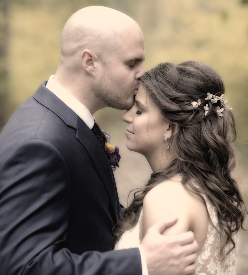 A man in a suit kisses a woman on the forehead