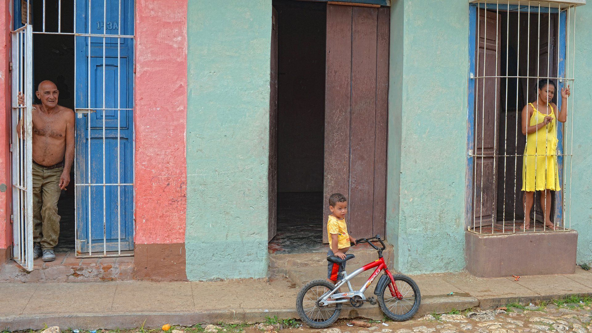 A man and a woman are standing in front of a building with a bicycle parked in front of it.