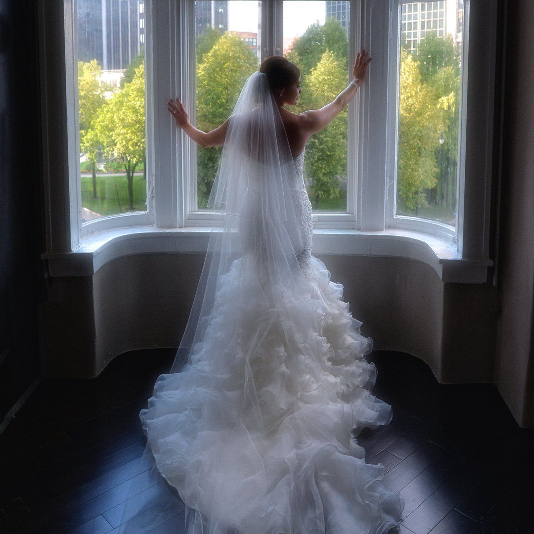 A woman in a wedding dress is standing in front of a window