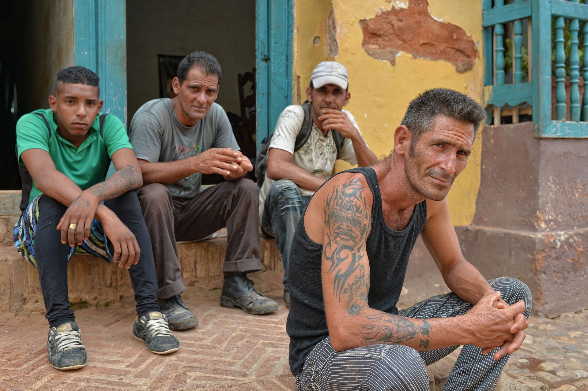 A group of men are sitting on the steps of a building.