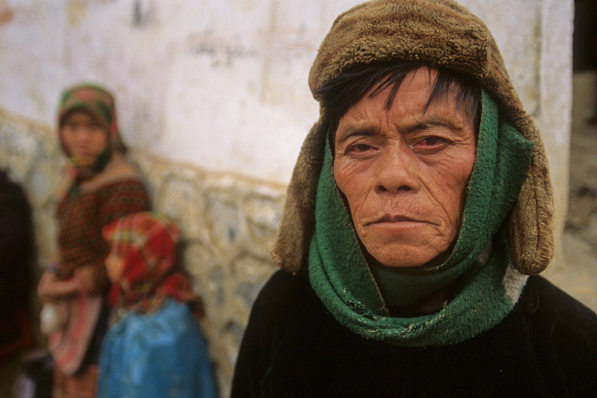 A man wearing a hat and a green scarf around his neck.