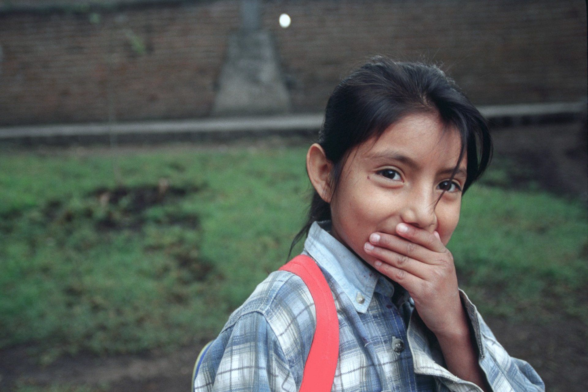 A young girl is covering her mouth with her hand.