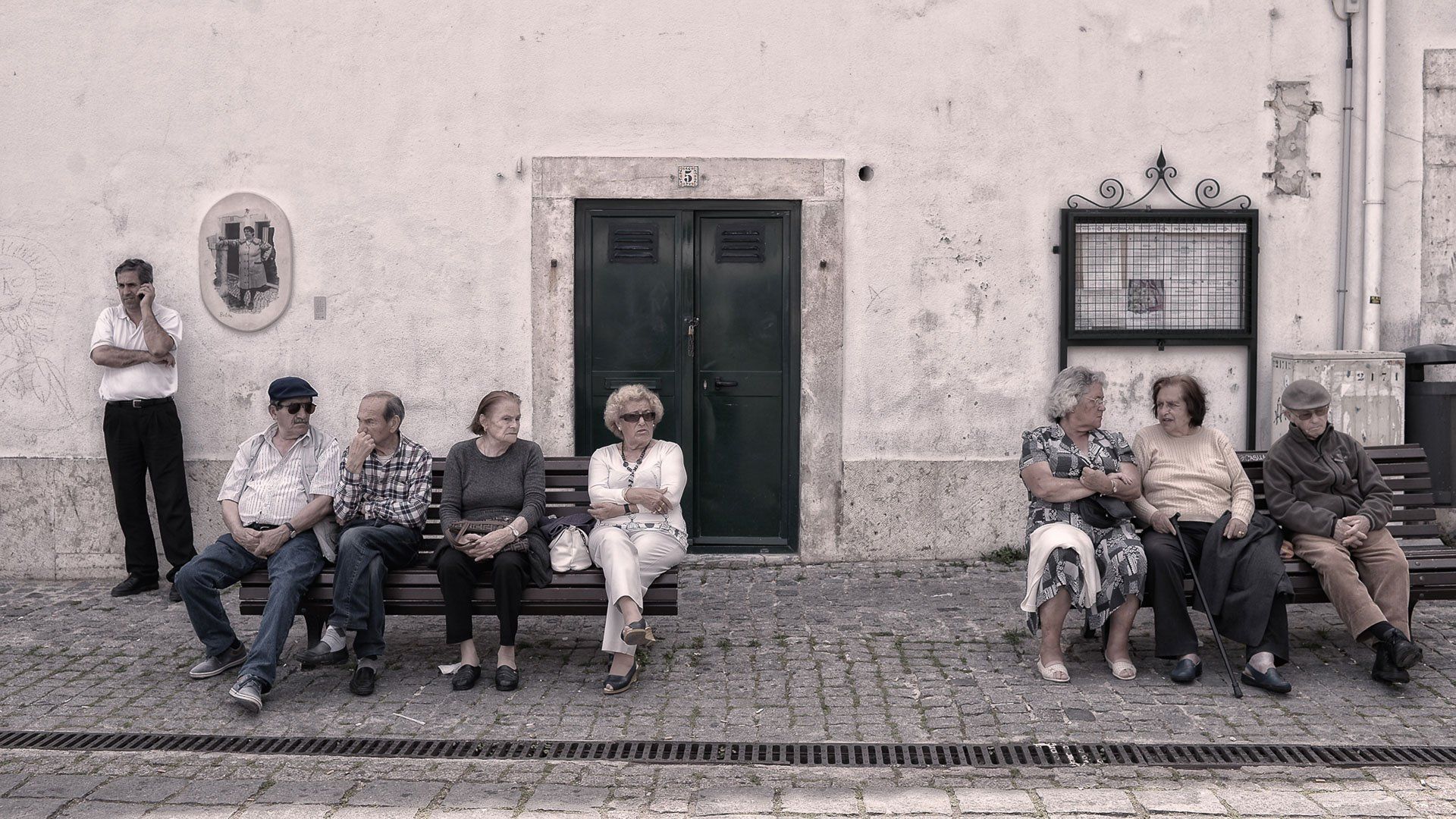 A group of people are sitting on a bench in front of a building.